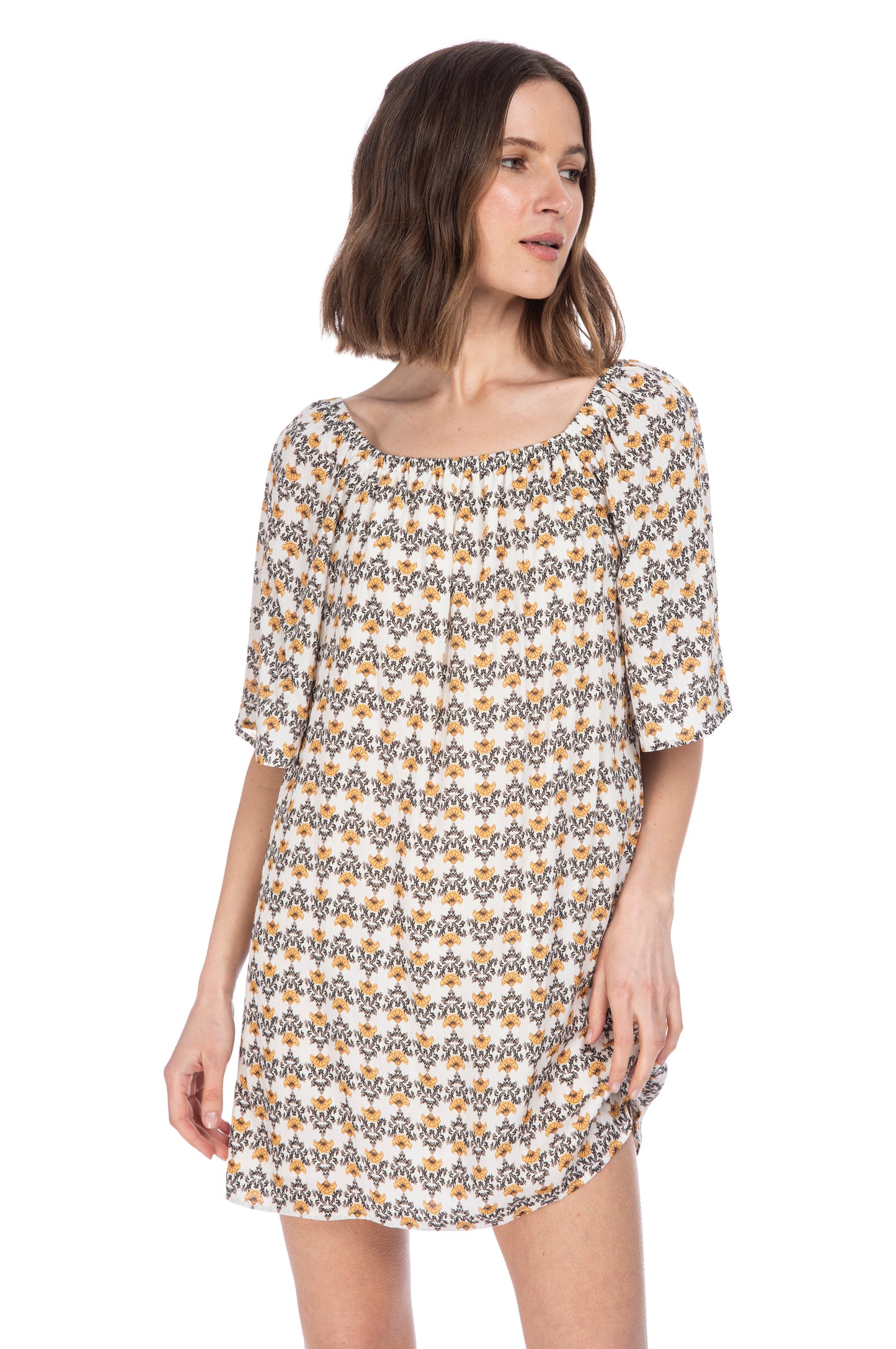 A woman in a versatile floral print dress with an off shoulder design and short sleeves, posing against a white background, wearing the ELBOW SLV SHIFT DRESS by B Collection by Bobeau.