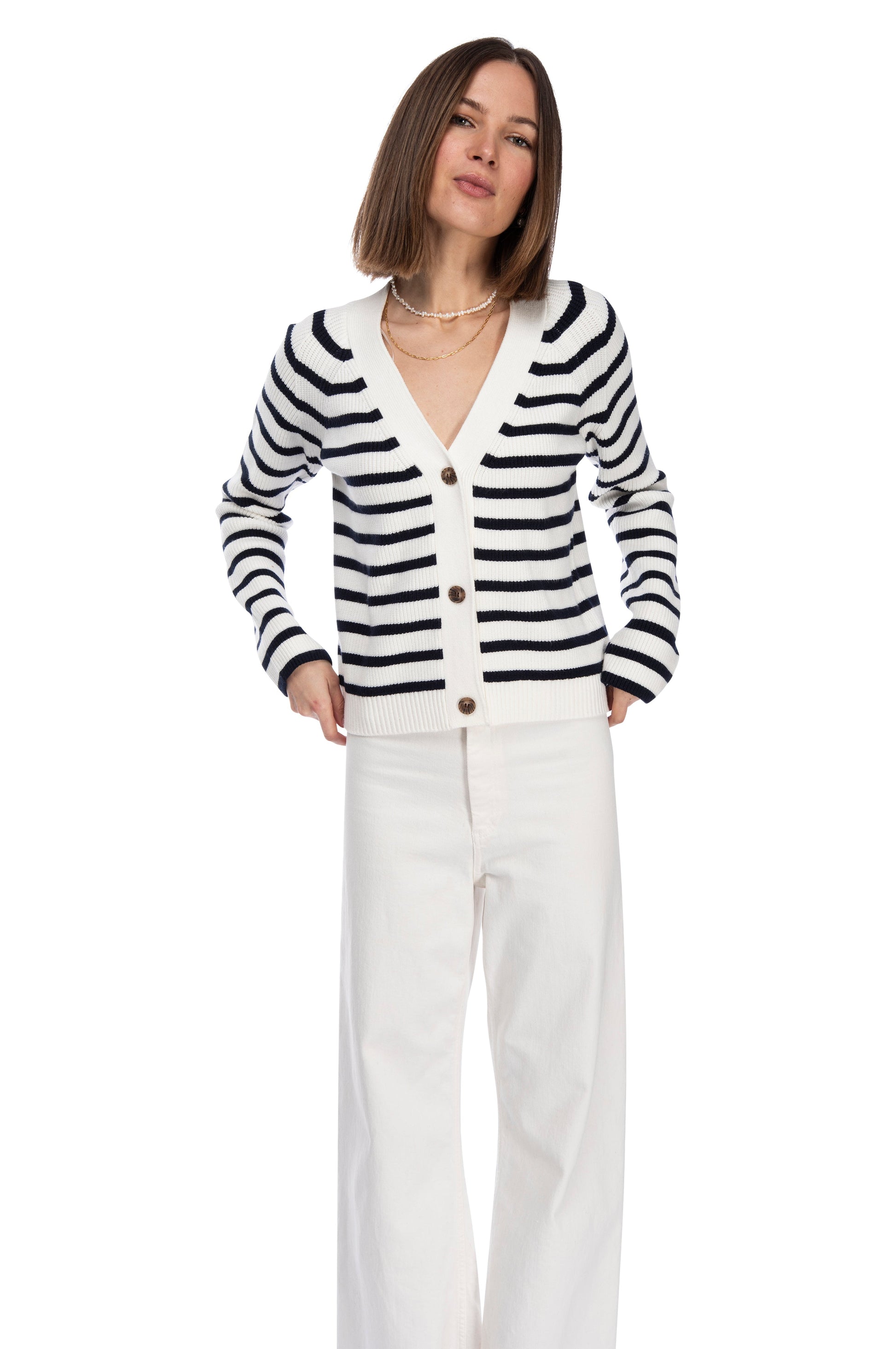 A woman standing confidently, dressed in a chic LS STRIPE CARDIGAN crafted from super soft yarn and white pants against a clean white background by B Collection by Bobeau.