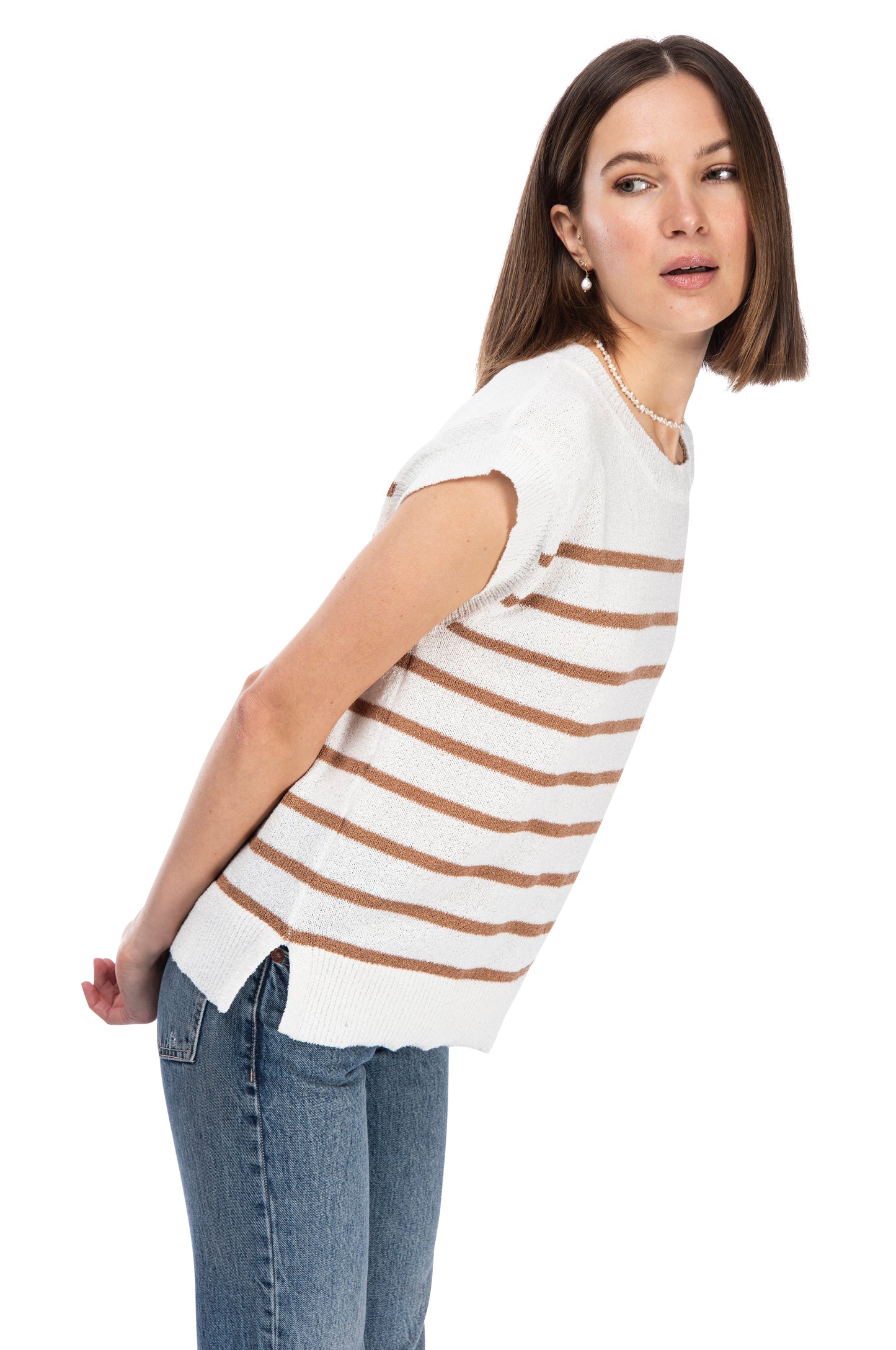 A woman in a casual B Collection by Bobeau crew neck stripe sweater top and jeans standing sideways, with one hand in her back pocket, and looking towards the camera with a subtle expression.