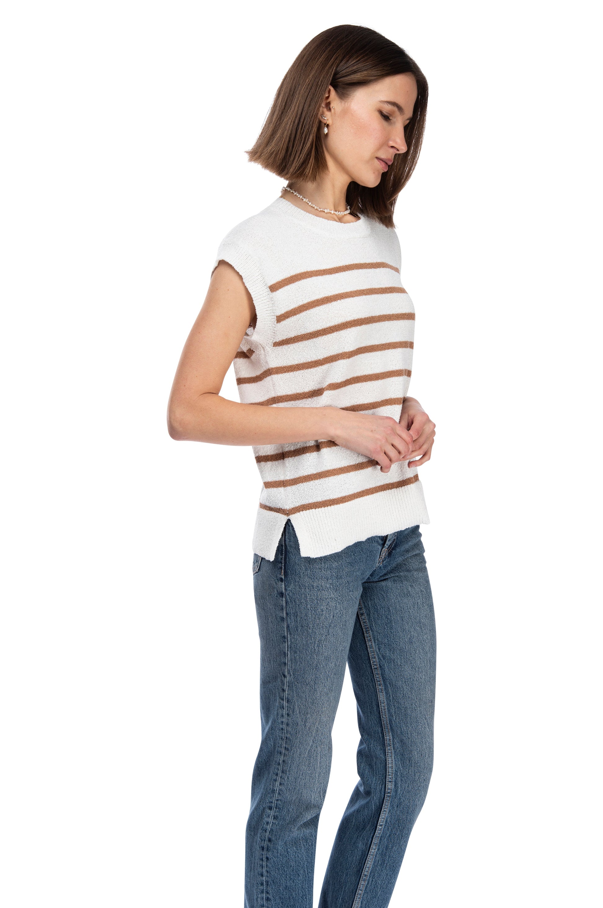 A woman in a B Collection by Bobeau CREW NECK STRIPE SWEATER TOP and jeans standing against a white background, looking down to her right with a mild, thoughtful expression.