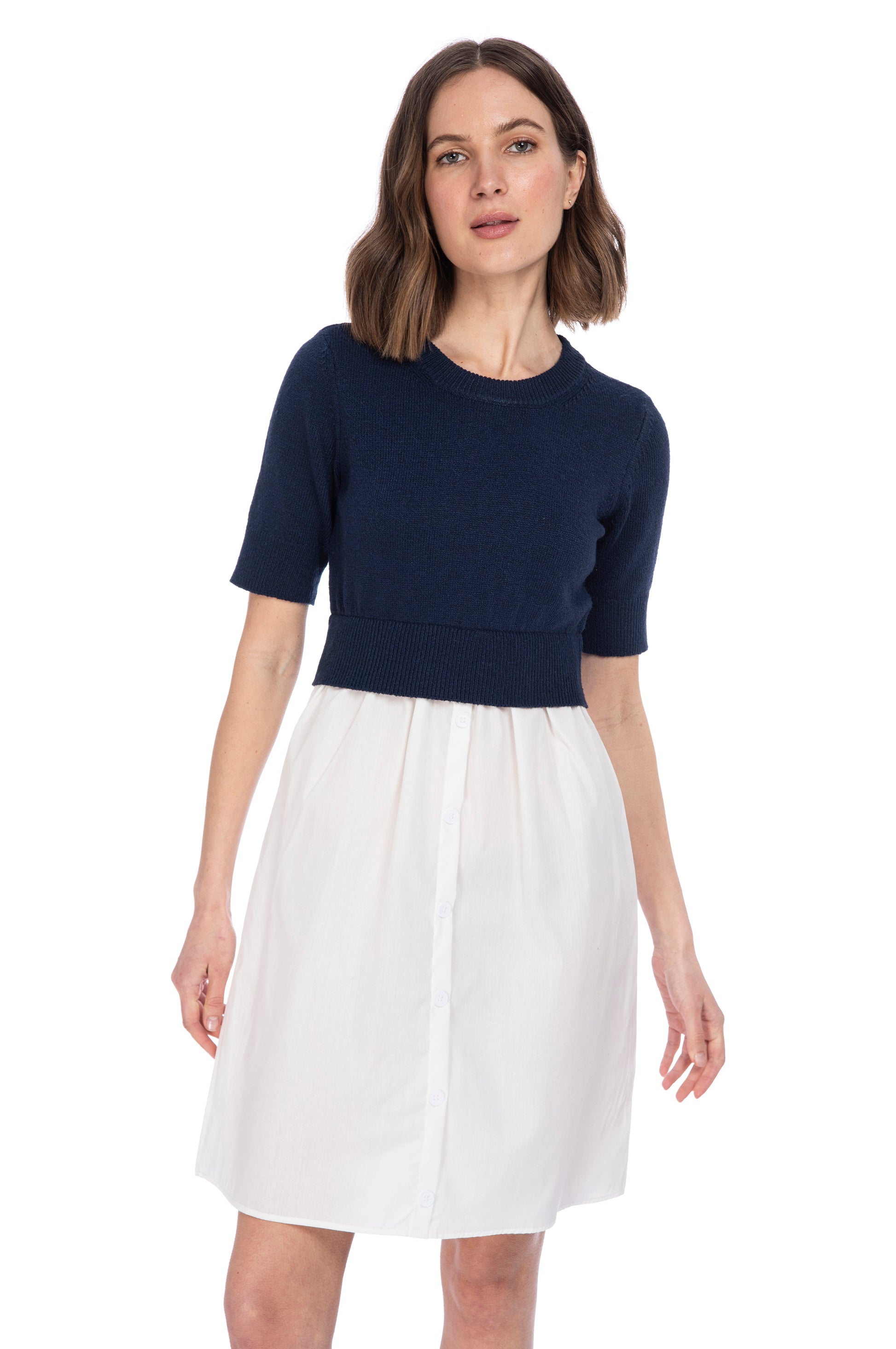 A woman in a stylish navy blue striped sweater vest from B Collection by Bobeau and a white poplin knee-length skirt posing against a white background.