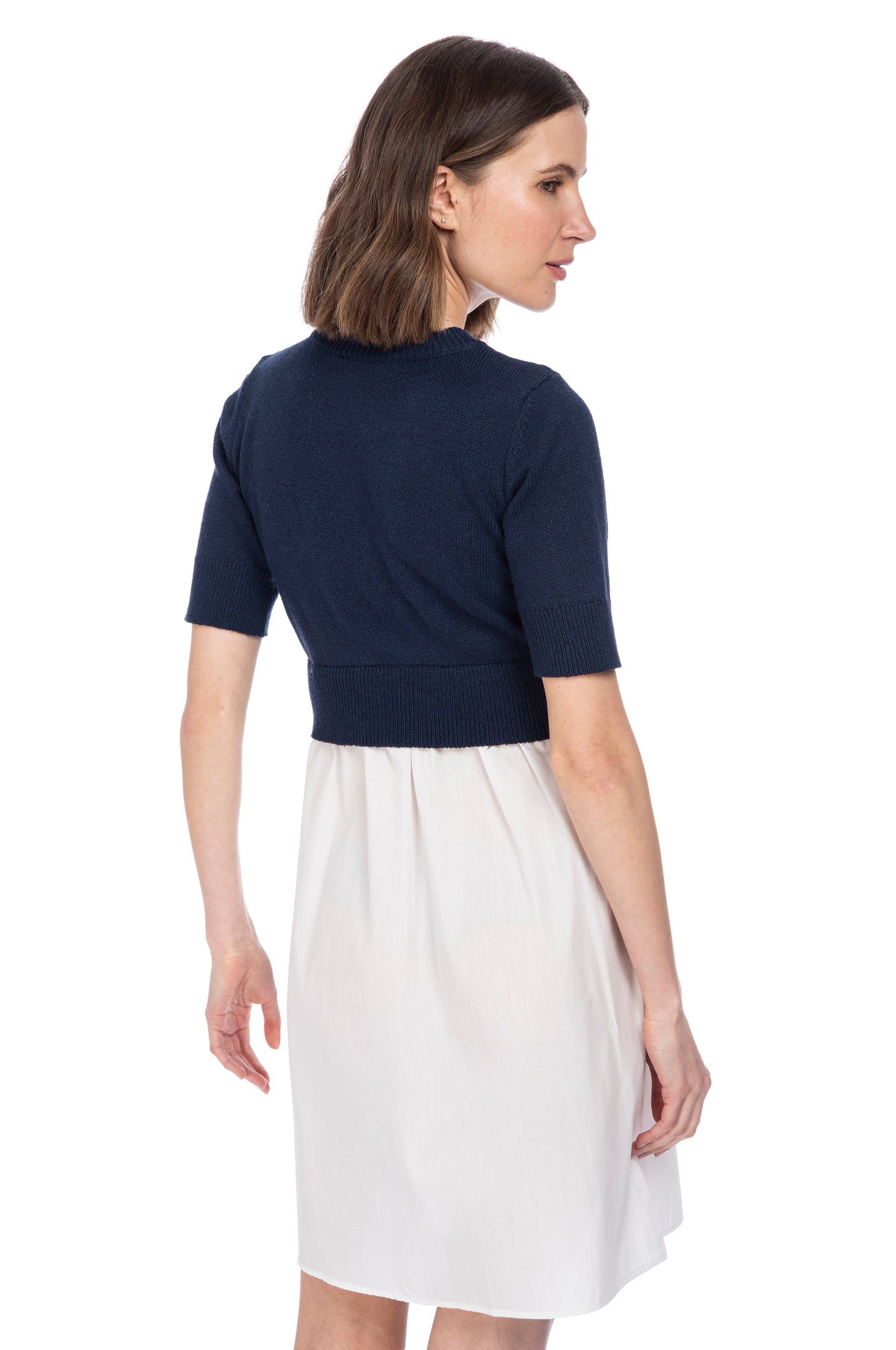 A woman posing sideways, wearing a half-sleeved navy blue striped sweater vest from B Collection by Bobeau and a white poplin knee-length skirt.