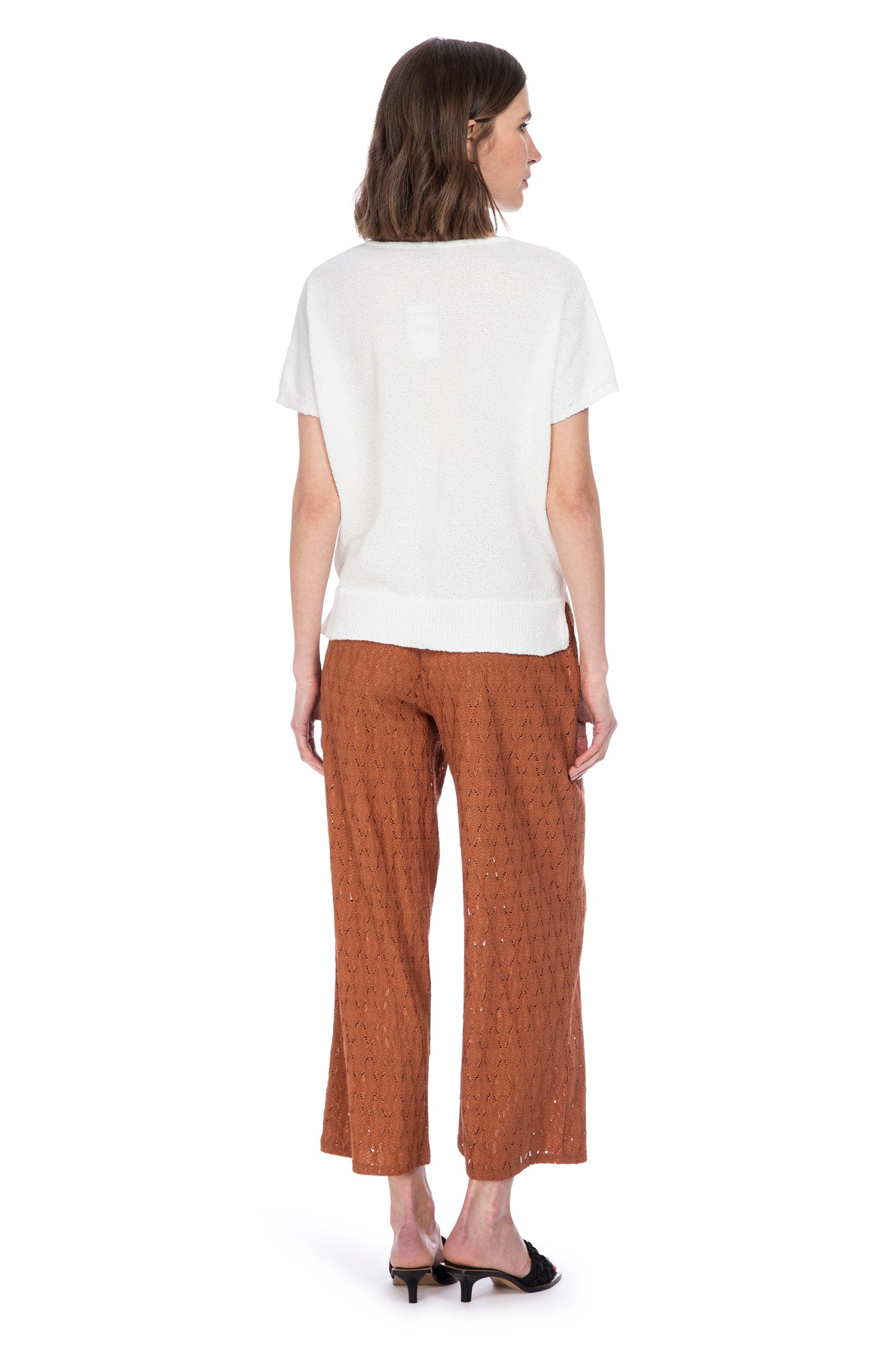A woman seen from behind, wearing a casual white t-shirt paired with stylish brown elastic waist ANKLE LENGTH PANTS in a lace-patterned stretch pointelle knit and classic black heels by B Collection by Bobeau.