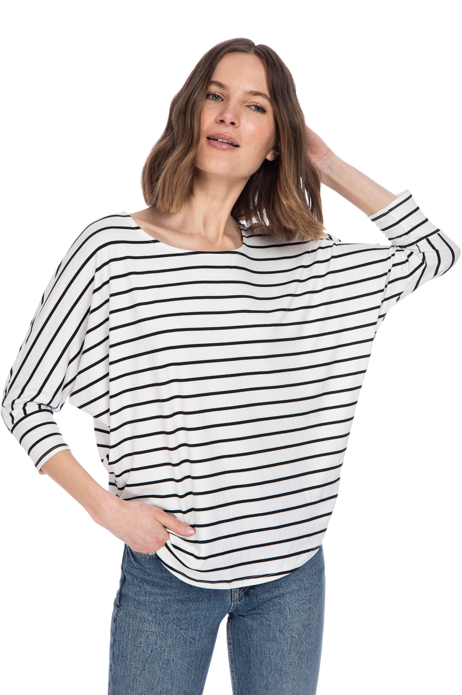 A woman in a casual pose wearing a black and white striped 3/4 SLV DOLMAN BUTTER TOP by B Collection by Bobeau and blue jeans against a white background.