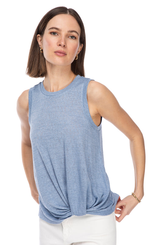 A confident woman posing in a casual CATY TWIST HEM CREW top by B Collection by Bobeau and white pants, with a subtle, determined expression on her face.
