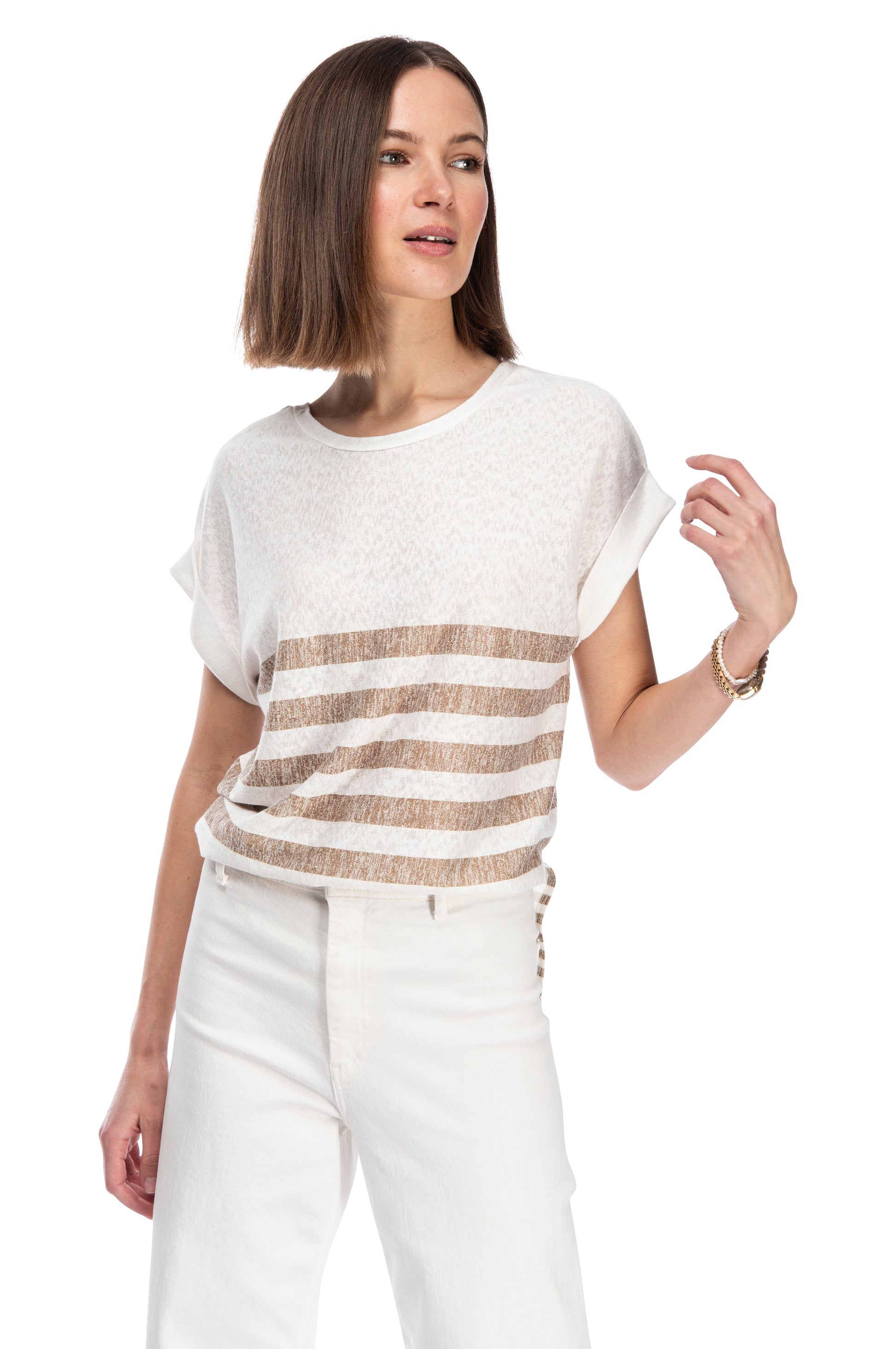 A woman in a casual white CATY STRAP TUNIC TEE by B Collection by Bobeau with placement stripe, paired with white pants, looking to the side with a contemplative expression.