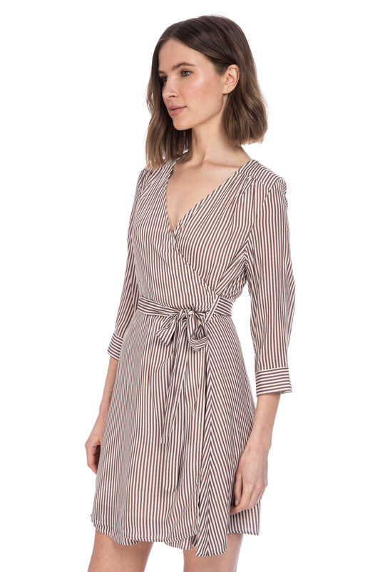 A woman posing in a B Collection by Bobeau WILLA STRIPE WRAP DRESS with a v-neck and three-quarter length sleeves, fully lined.