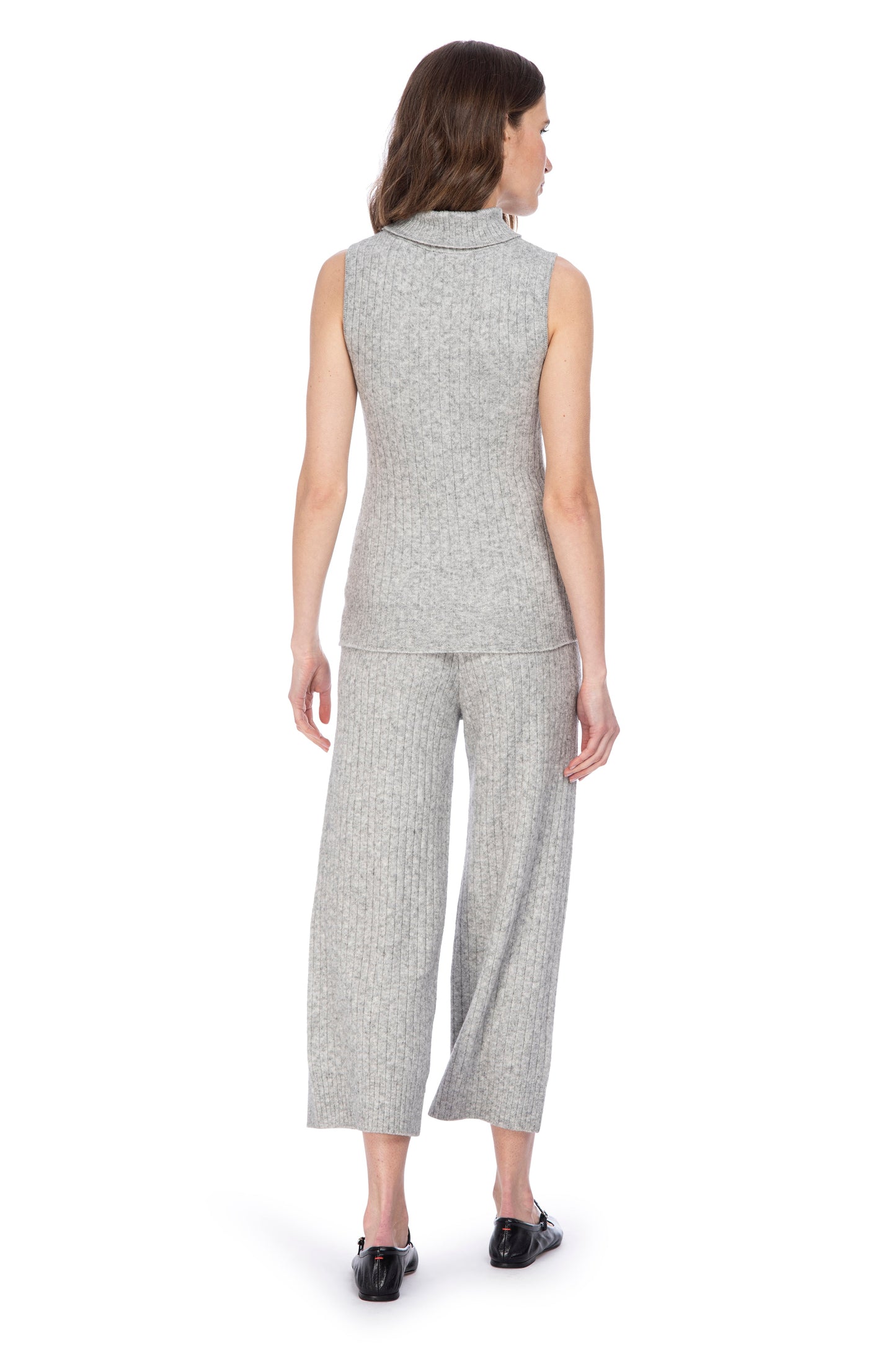 A woman from behind, wearing a chic sleeveless B Collection by Bobeau turtleneck sweater top in gray and matching cropped trousers, paired with black shoes.