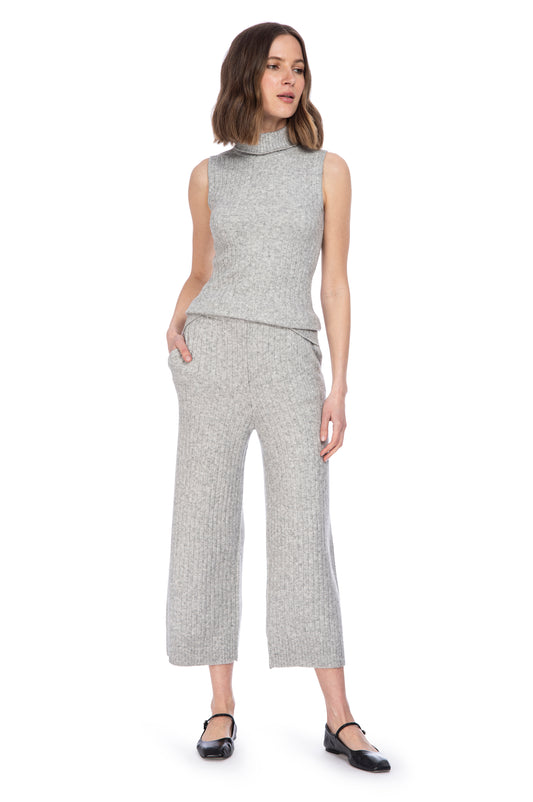 A woman modeling a sleeveless turtleneck RIBBED SWEATER PANTS W/ POCKETS and matching cropped pants in a textured grey fabric, paired with black heels from B Collection by Bobeau.