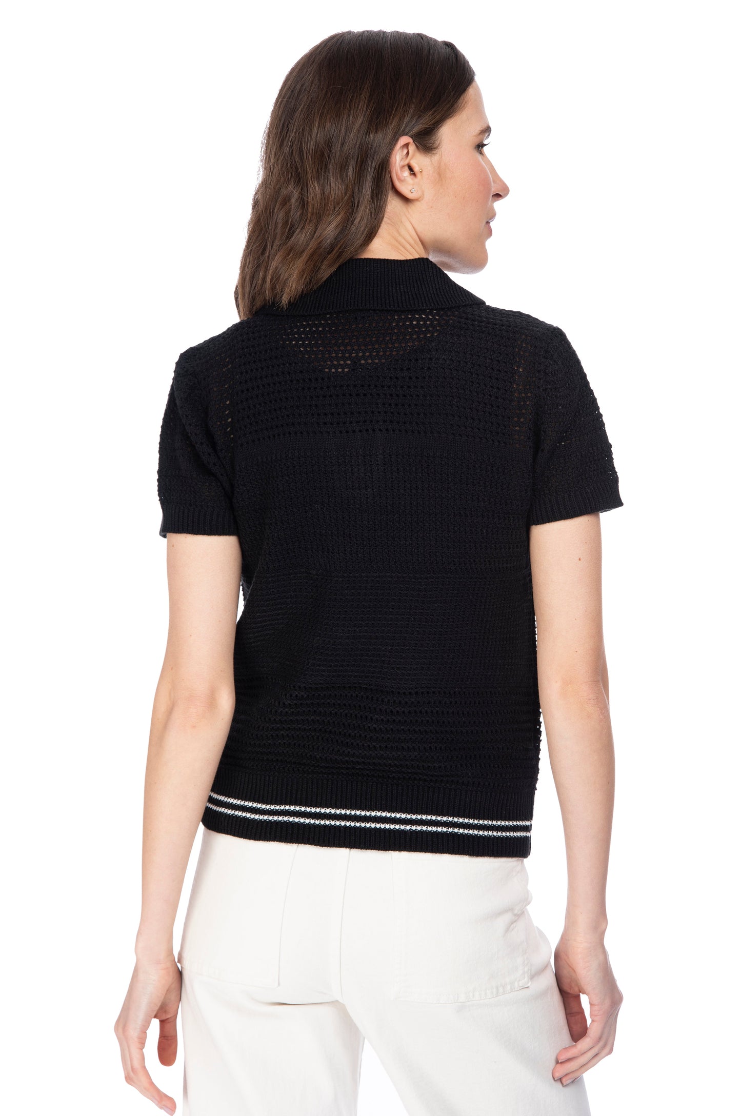 A woman photographed from behind, wearing a black short-sleeve B Collection by Bobeau POLO OPEN WEAVE SWEATER and white pants with racer stripe detail.