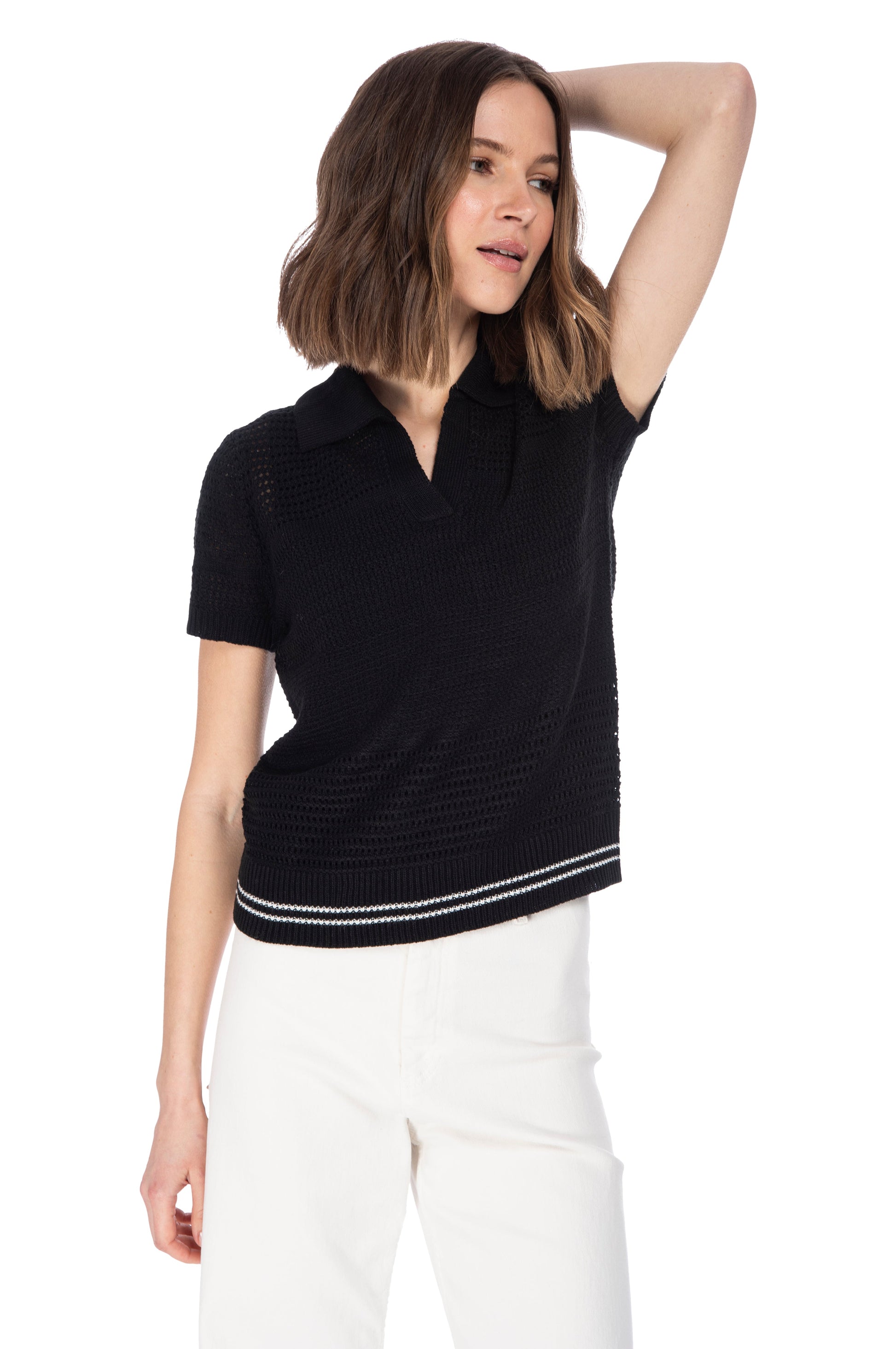 A woman in a stylish black short-sleeved top with racer stripe detail (B Collection by Bobeau) and white pants posing with one hand behind her head.