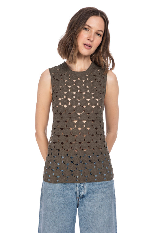 A woman wearing a CROCHET FLORAL TANK in brown with a geometric cut-out pattern paired with blue jeans standing against a white background by B Collection by Bobeau.