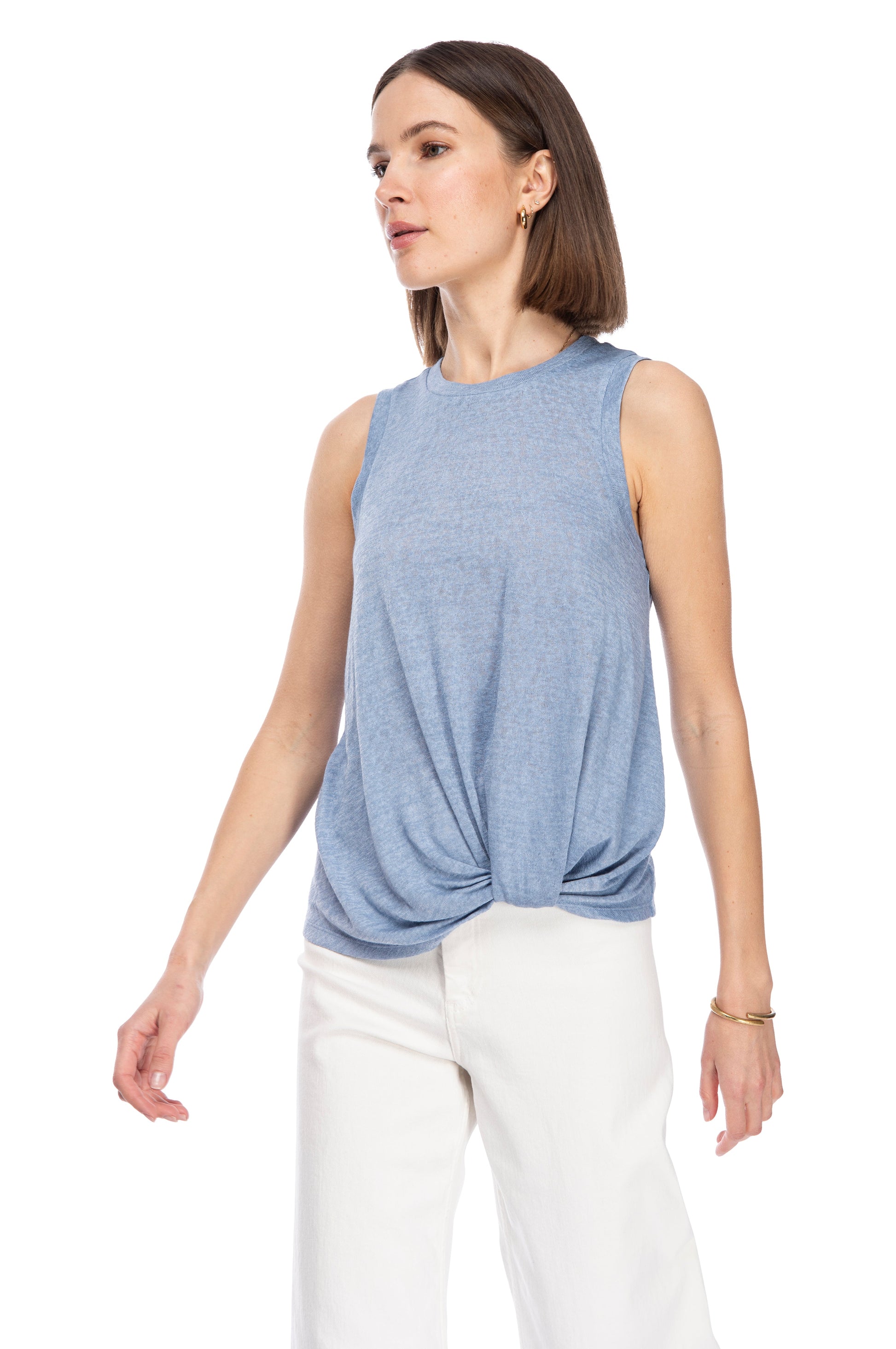 A person in a casual sleeveless blue CATY TWIST HEM CREW knit top and white pants posing against a white background. (B Collection by Bobeau)