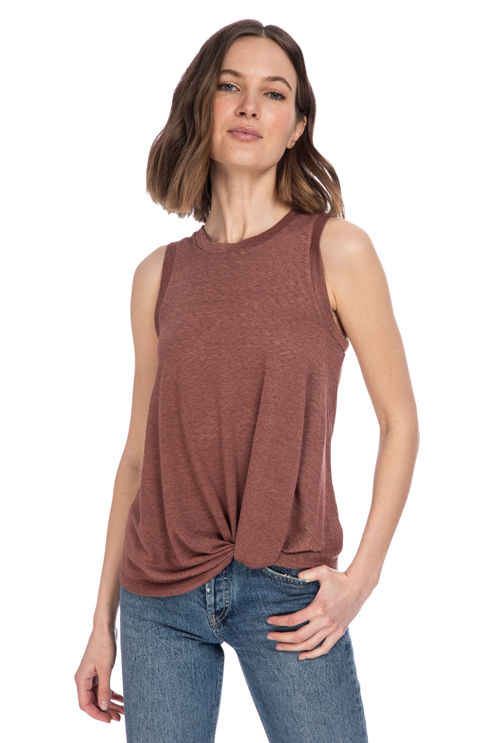 A woman in a B Collection by Bobeau CATY TWIST HEM CREW knit top with a twist hem and blue jeans posing with one hand in her pocket.