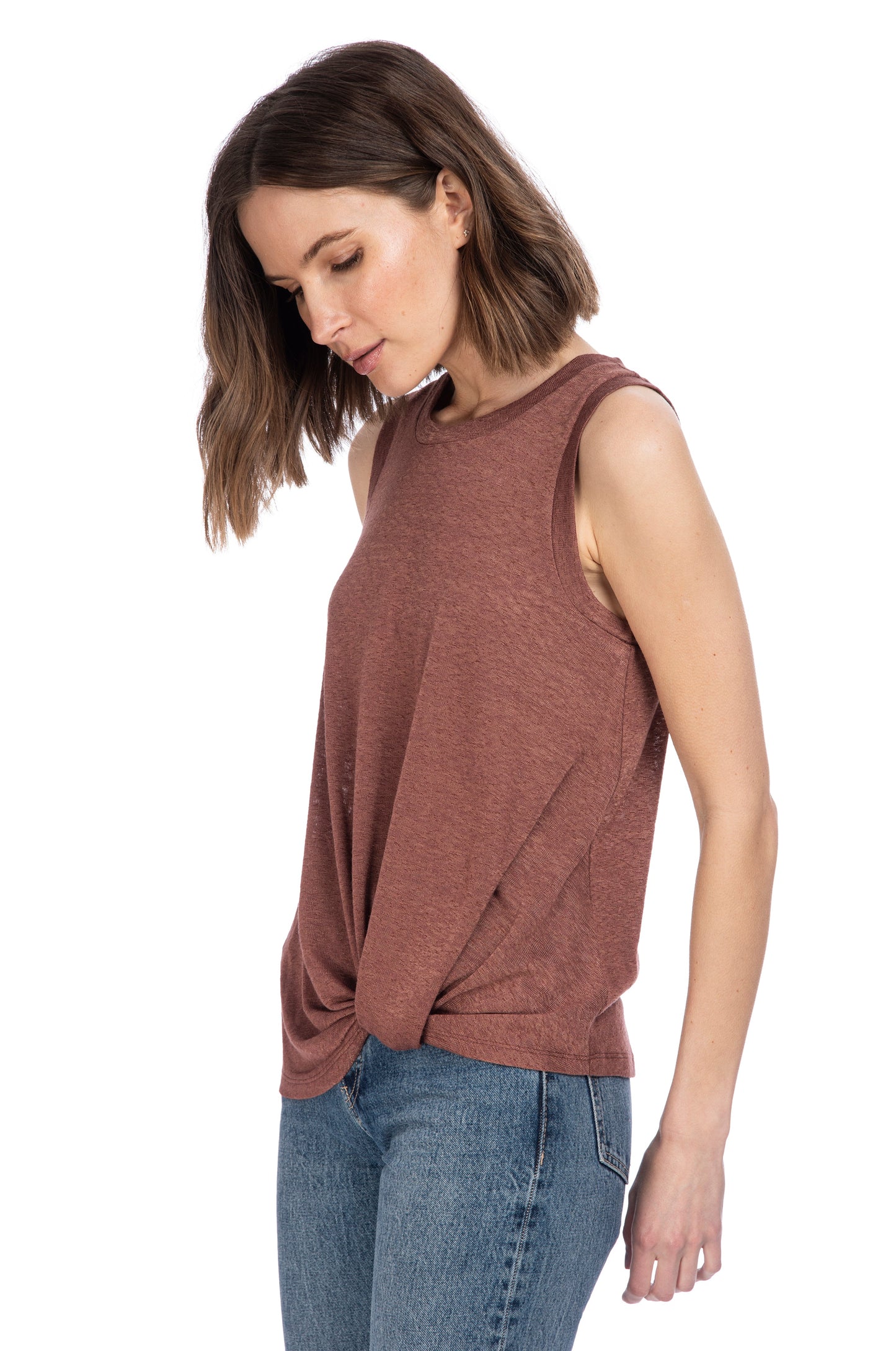 A woman in a casual CATY TWIST HEM CREW top by B Collection by Bobeau and jeans, looking down to her side with a relaxed posture.