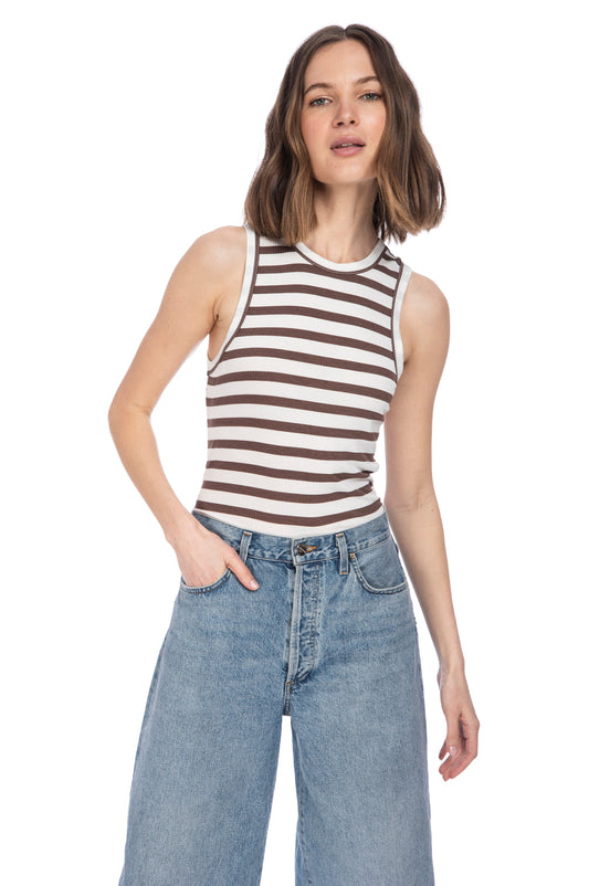 Woman posing in a B Collection by Bobeau HIGH NECK TANK and high-waisted jeans against a white background.