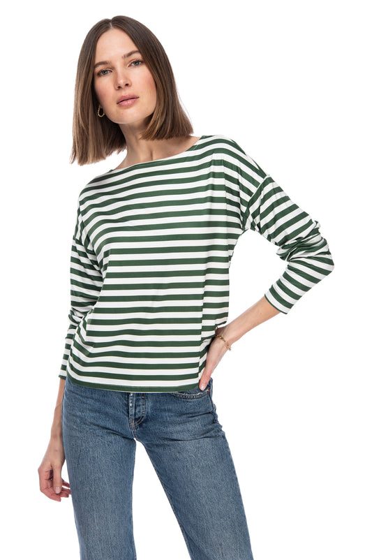 A confident woman in a FRENCH BATEAU BUTTER TEE by B Collection by Bobeau featuring a French girl stripe design, paired with classic blue jeans, strikes a casual pose.