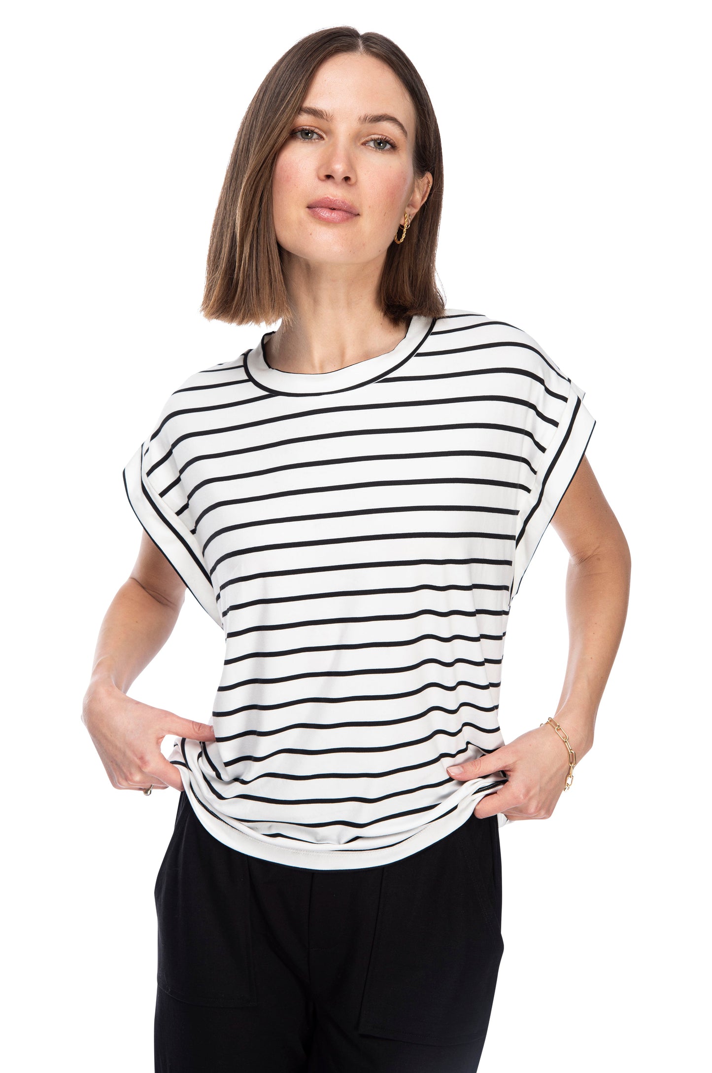 A woman in a black and white striped, crewneck top made from Butter Knit Jersey poses with one hand lifting the hem of her B Collection by Bobeau Drop Armhole Tee.