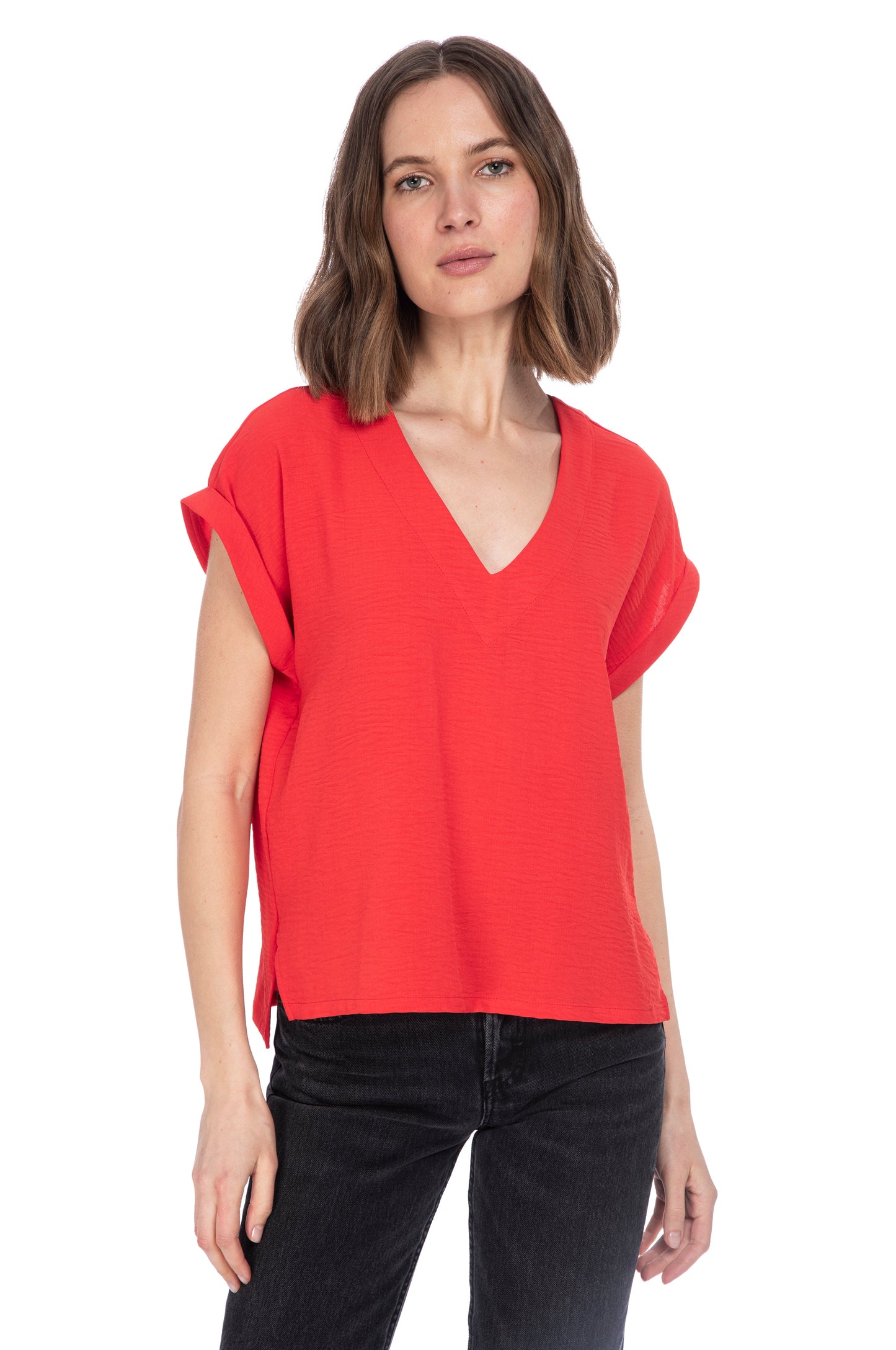 A woman with shoulder-length hair wearing a red V Neck Relaxed Woven Tee made of 100% Polyester and black jeans against a white background by B Collection by Bobeau.