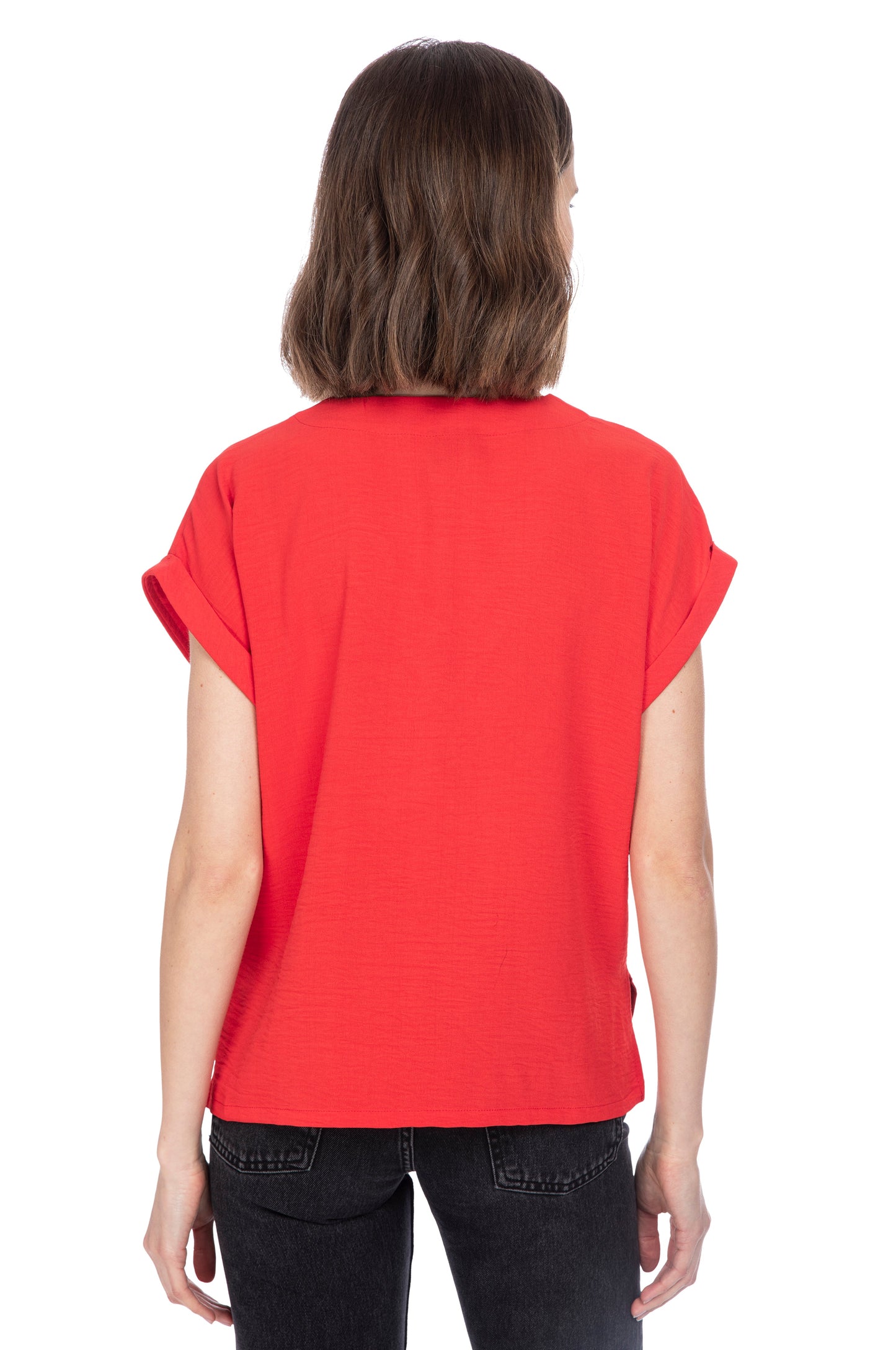 A woman seen from behind, wearing a vibrant red V NECK RELAXED WOVEN TEE made from 100% Polyester and black jeans, standing against a white background. Brand Name: B Collection by Bobeau