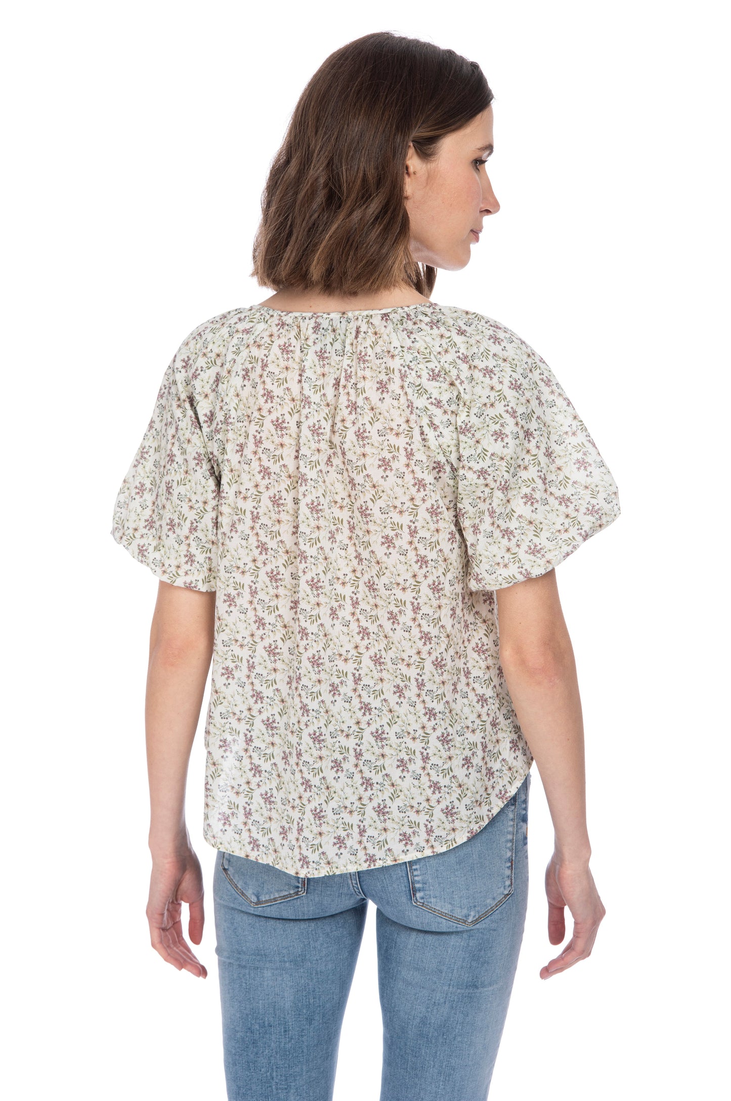 Woman seen from the back wearing a floral patterned crewneck B Collection by Bobeau bubble sleeve cotton top and blue jeans.