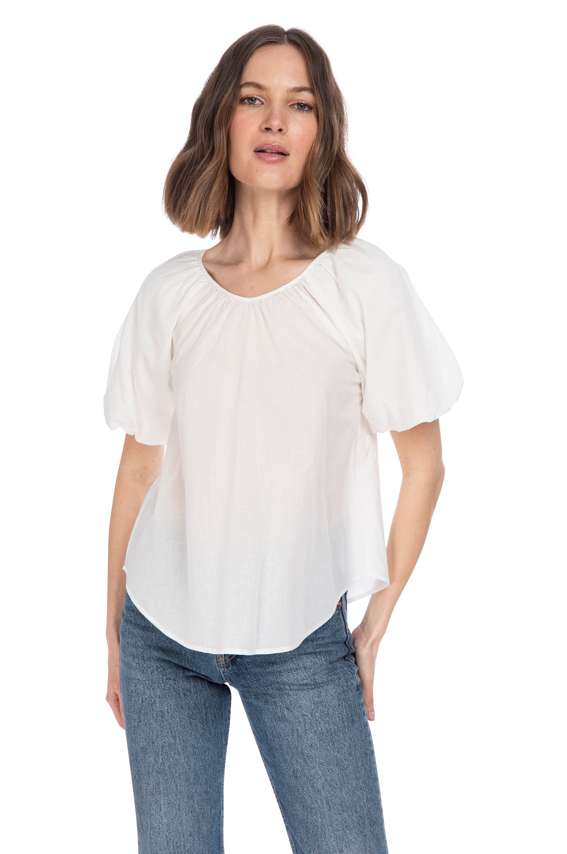 A woman wearing a B Collection by Bobeau Bubble Sleeve Cotton Top and blue jeans standing against a white background.