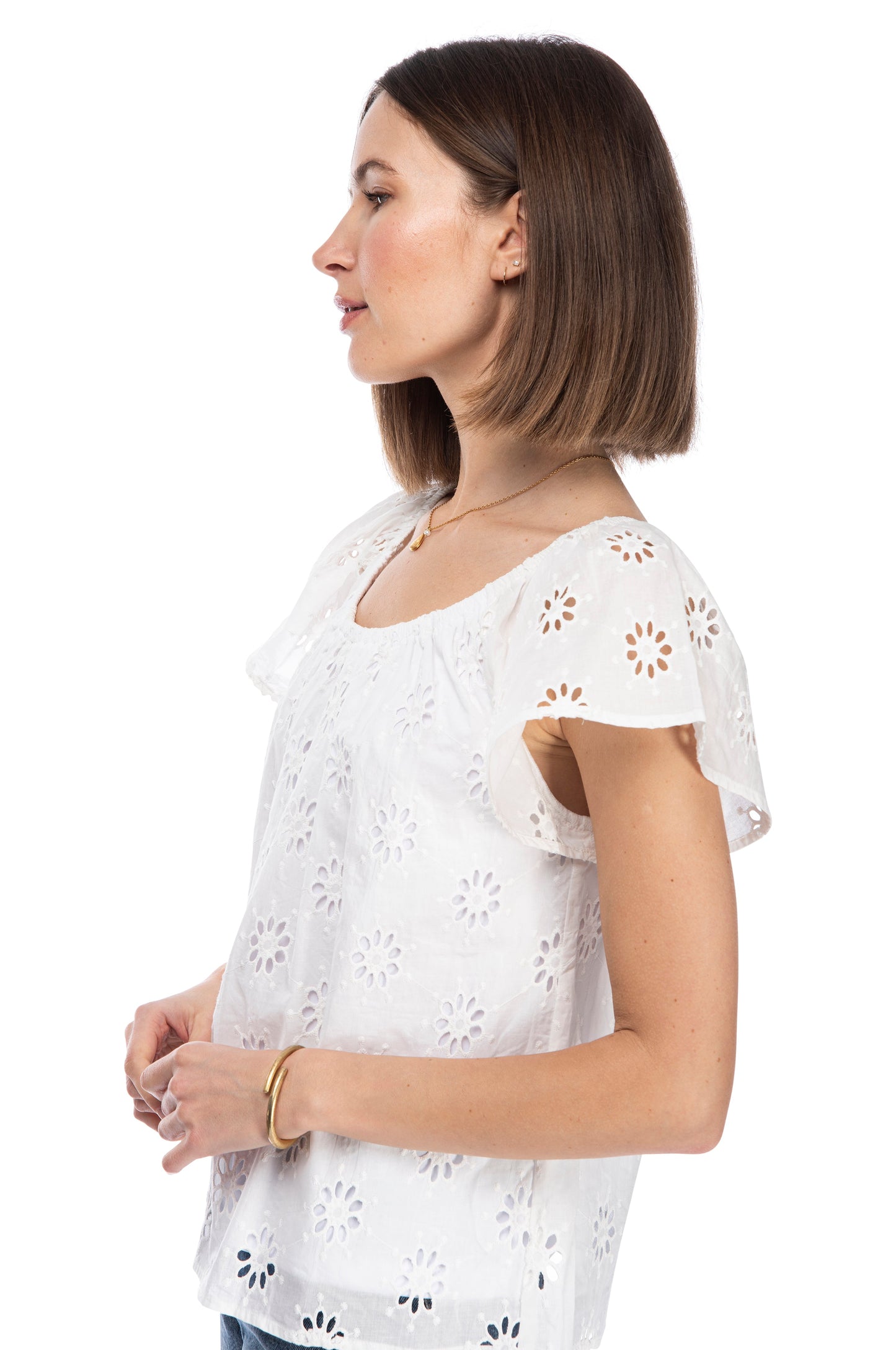 A woman in a white eyelet SS Peasant Top with a floral pattern, looking to the side with a calm expression, isolated on a white background by B Collection by Bobeau.