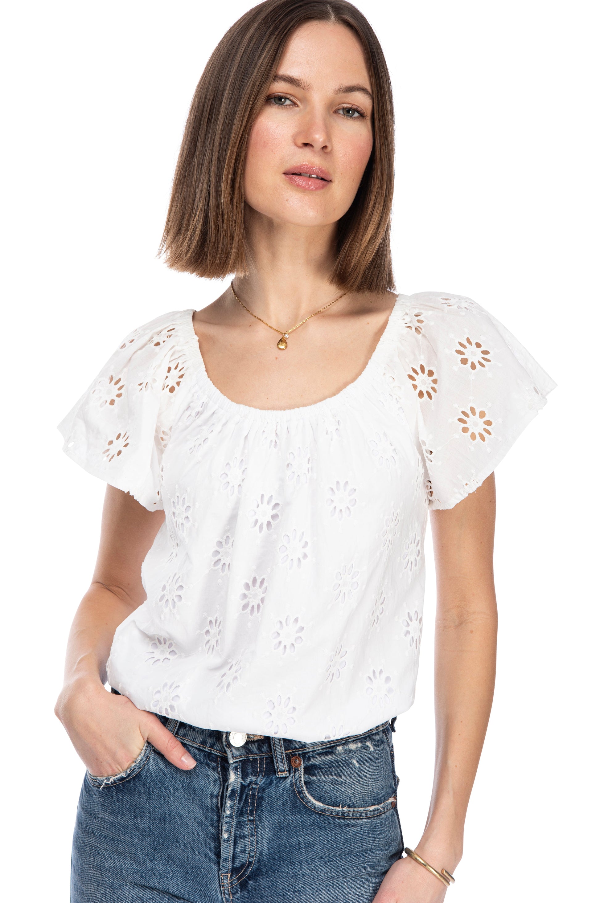 Woman in a stylish B Collection by Bobeau eyelet short sleeve blouse with floral cut-out designs paired with classic denim jeans, exuding casual elegance.