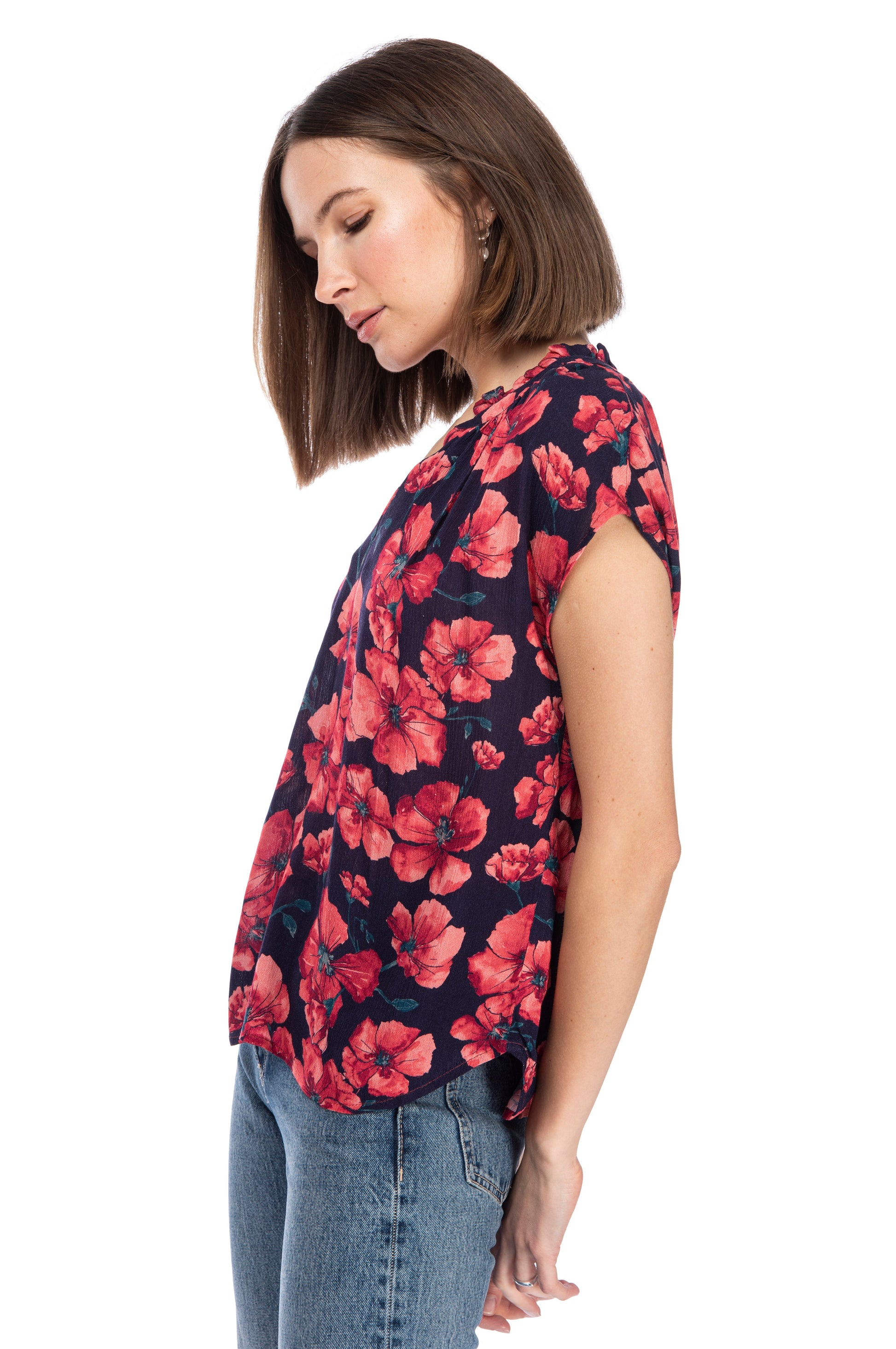 A woman in a Ruffle Neck Top from B Collection by Bobeau and jeans in a side profile pose against a white background.