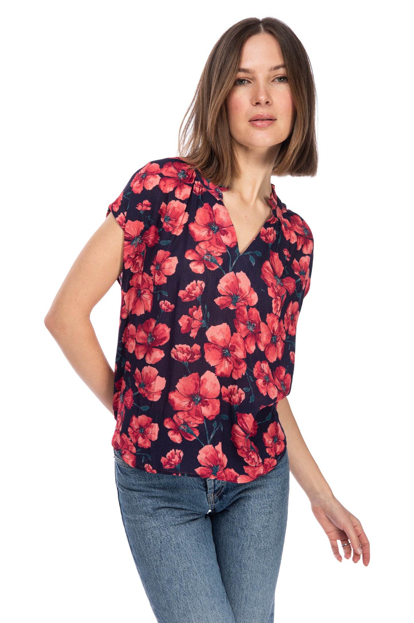 Woman posing in a B Collection by Bobeau 100% Rayon floral ruffle neck top and blue jeans against a white background.
