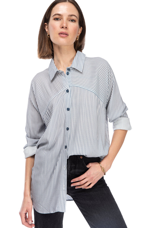 A woman in a casual striped LS BTTN DOWN TUNIC by B Collection by Bobeau with a lapel collar and dark jeans posing for the camera.